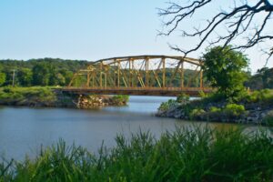 Photo of a large yellow bridge across Lake Texoma in Texas with green trees on each side