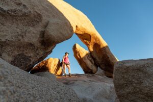 Photo of a woman in a pink top under a rock formation
