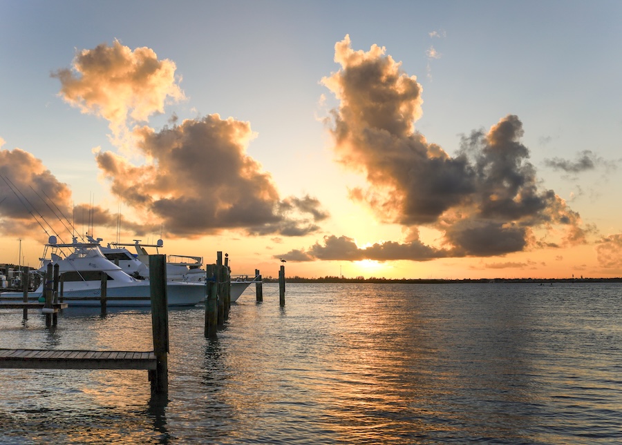 Photo of a sunset over a marina, with a few empty docks and a larger white yacht parked at the end