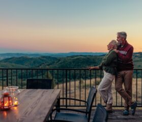 Photo of a retired couple enjoying their fall vacation with mountains in the background