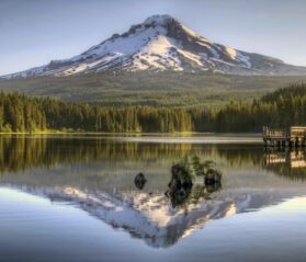 Photo of Mount Hood with snow on top, reflected in a lake with green trees