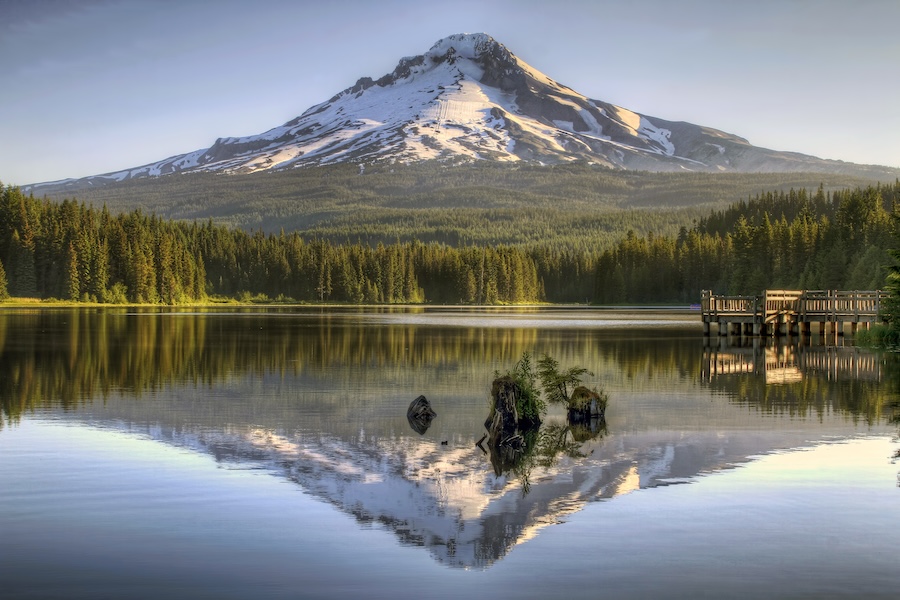 Photo of Mount Hood with snow on top, reflected in a lake with green trees