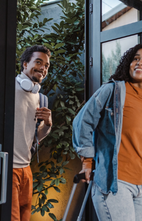 Two travelers smiling as they arrive at a vacation rental property — iTrip Vacation Rental Week social graphic