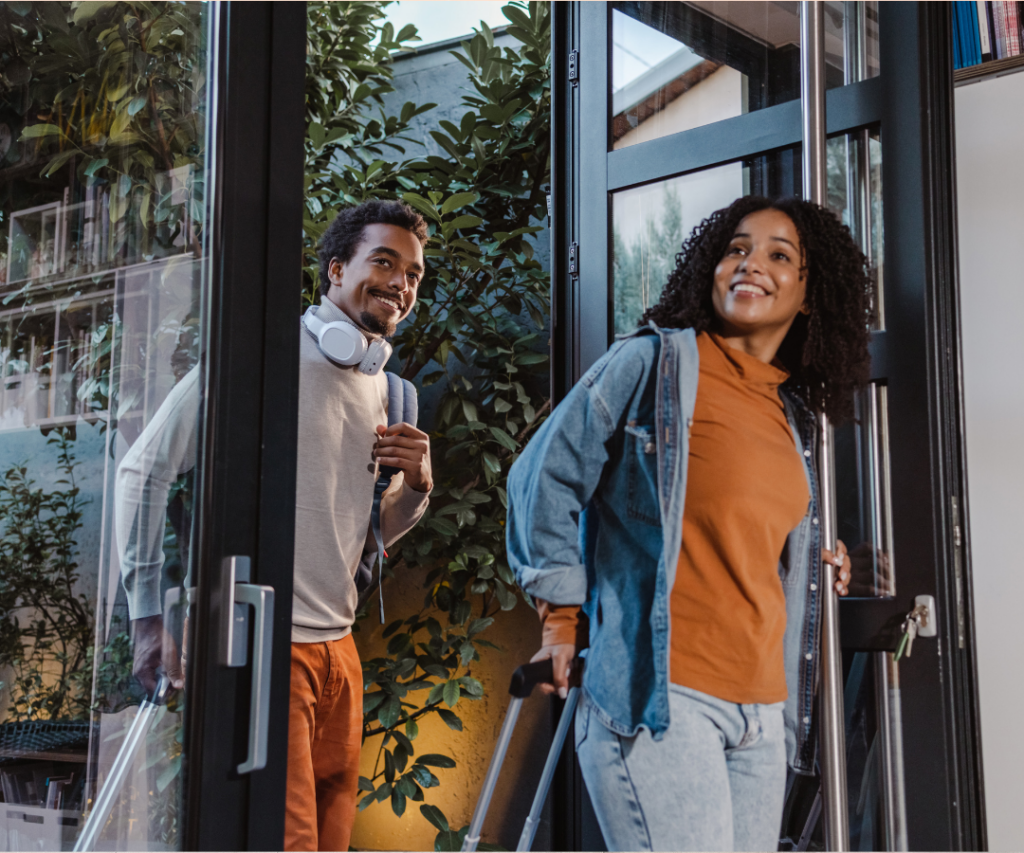 A couple walks into the front door of a vacation rental with smiles and pulling their suitcases